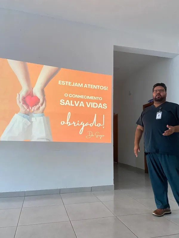 Dr. Sérgio ao lado do slide final O conhecimento salva vidas