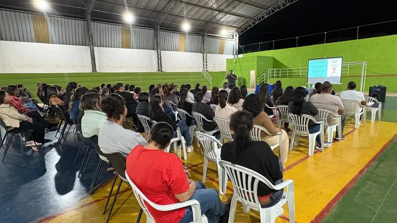 Ginásio cheio de profissionais da educação assistindo a uma palestra