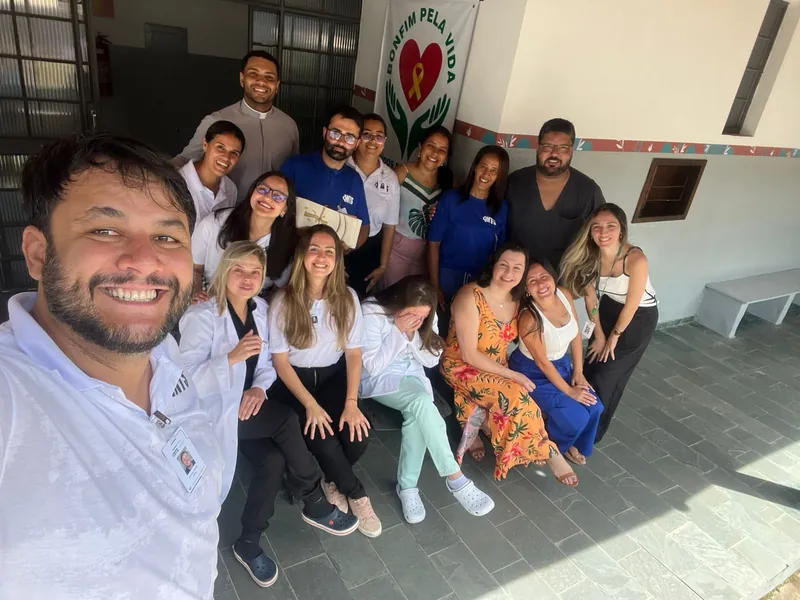 Selfie da equipe do CAPS I diante do muro com o coração da campanha