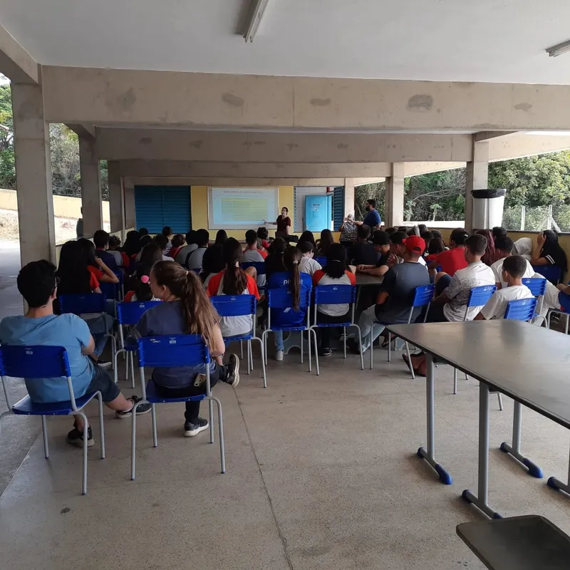 Estudantes do ensino médio assistem a uma palestra em um pátio coberto