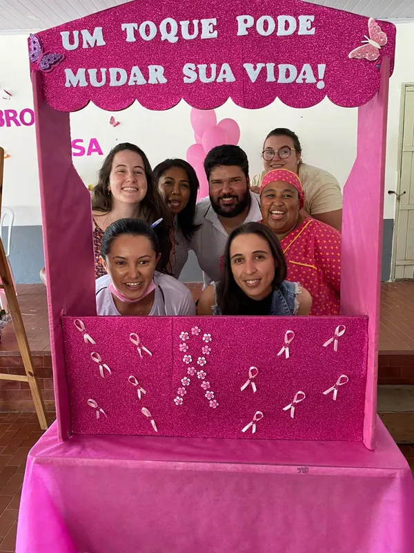 Equipe sorrindo dentro de uma moldura rosa com a frase Um toque pode mudar sua vida