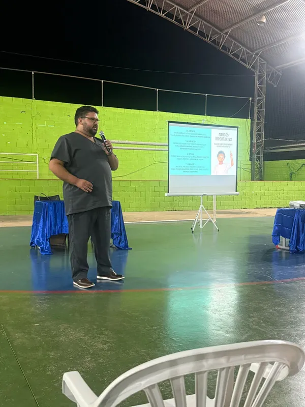 Dr. Sérgio ao microfone em um ginásio, à noite