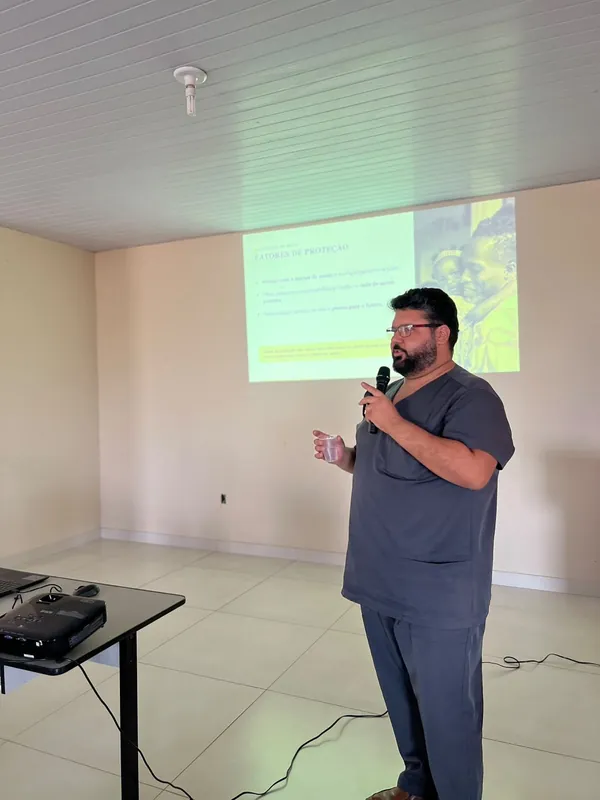 Dr. Sérgio ao microfone diante do slide Fatores de proteção